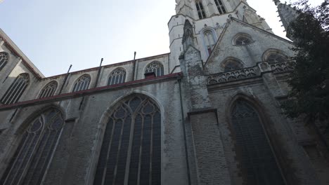 una vista cautivadora que mira hacia arriba a la intrincada fachada de una histórica catedral gótica, mostrando sus detalles arquitectónicos y su imponente presencia bajo un cielo azul claro.