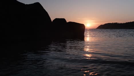 sunrise over a sea with rocks in foreground