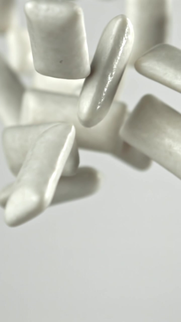 Pezzi di gomma da masticare che cadono al rallentatore su sfondo bianco