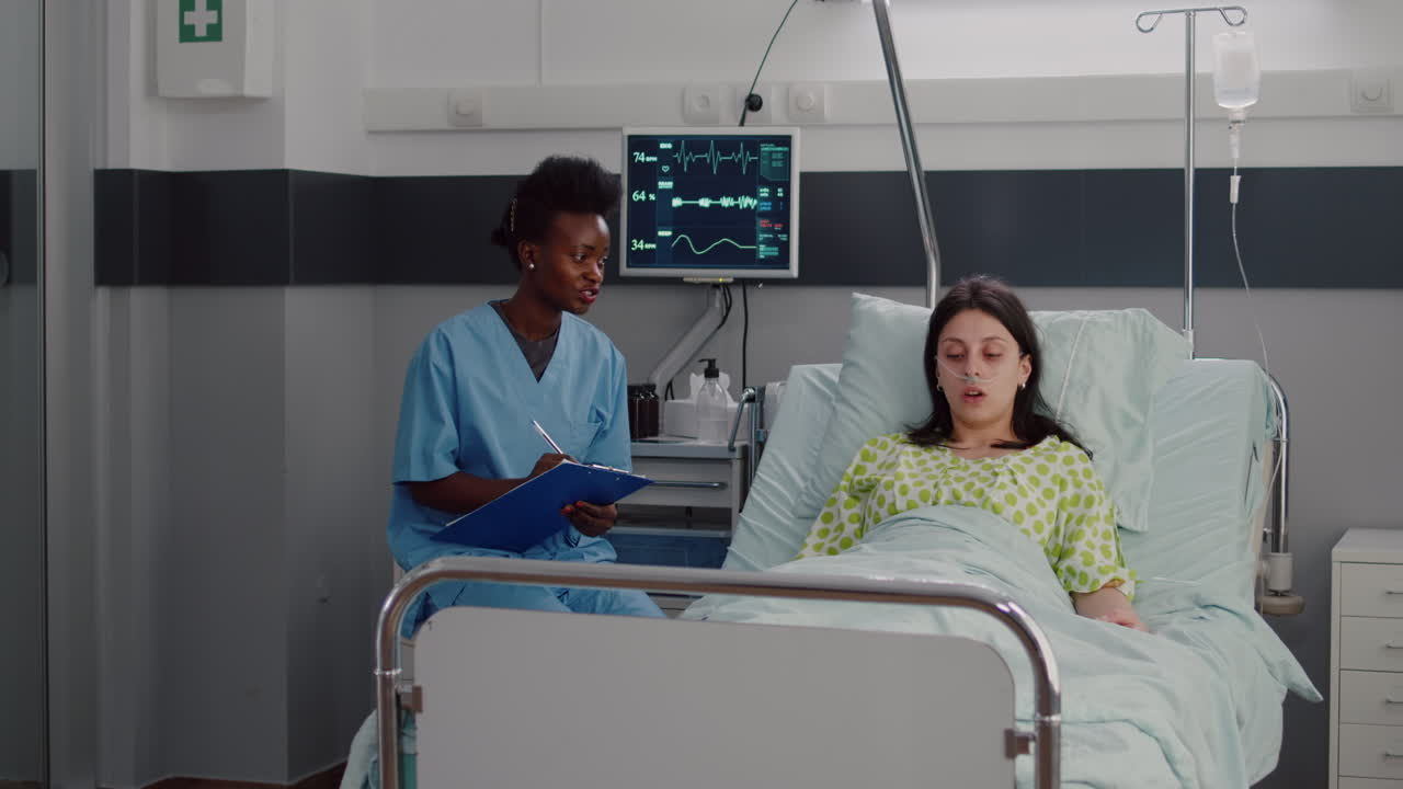 mujer enferma descansando en la cama mientras la enfermera afroamericana monitorea la enfermedad