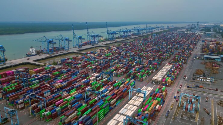 West port klang with stacks of colorful shipping containers and large cranes along the bustling dock. Tremendous aerial view overflight flyover drone