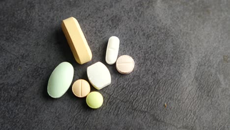 close up of various colorful pills on a dark surface