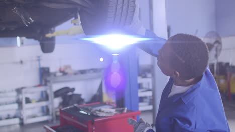 animation of light over african american male mechanic fixing car