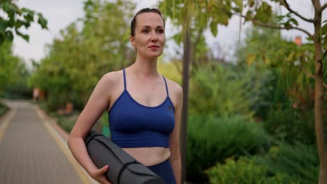 woman walking with yoga mat in a park