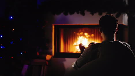 Young-Confident-Man-Resting-By-The-Fireplace-And-Christmas-Tree