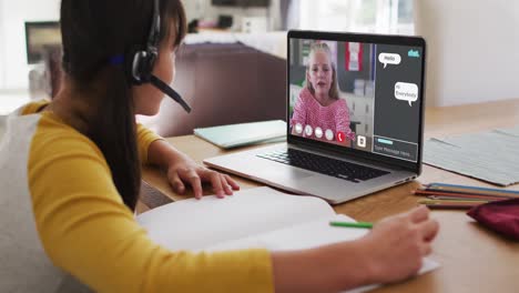 Schoolgirl-using-laptop-for-online-lesson-at-home,-with-girl-talking-and-web-chat-on-screen