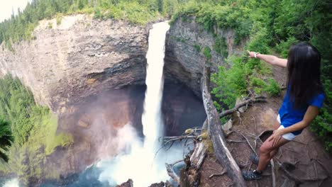 Mujer-Apuntando-Hacia-La-Cascada-En-El-Acantilado-4k