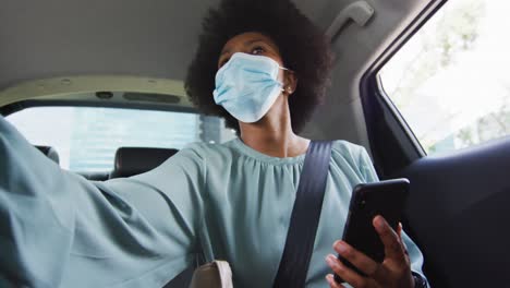 African american businesswoman with face mask using smartphone