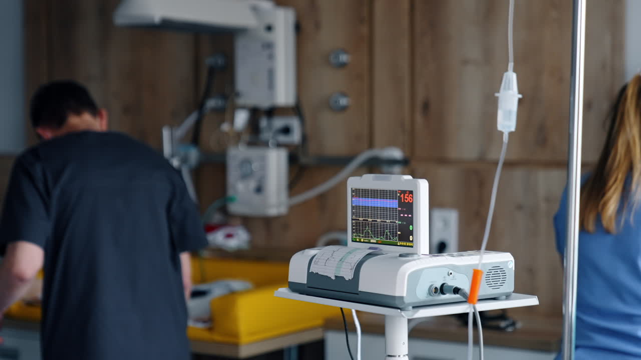 Cardiotocography equipment working in the delivery room. Medics preparing for labour at backdrop in blur.