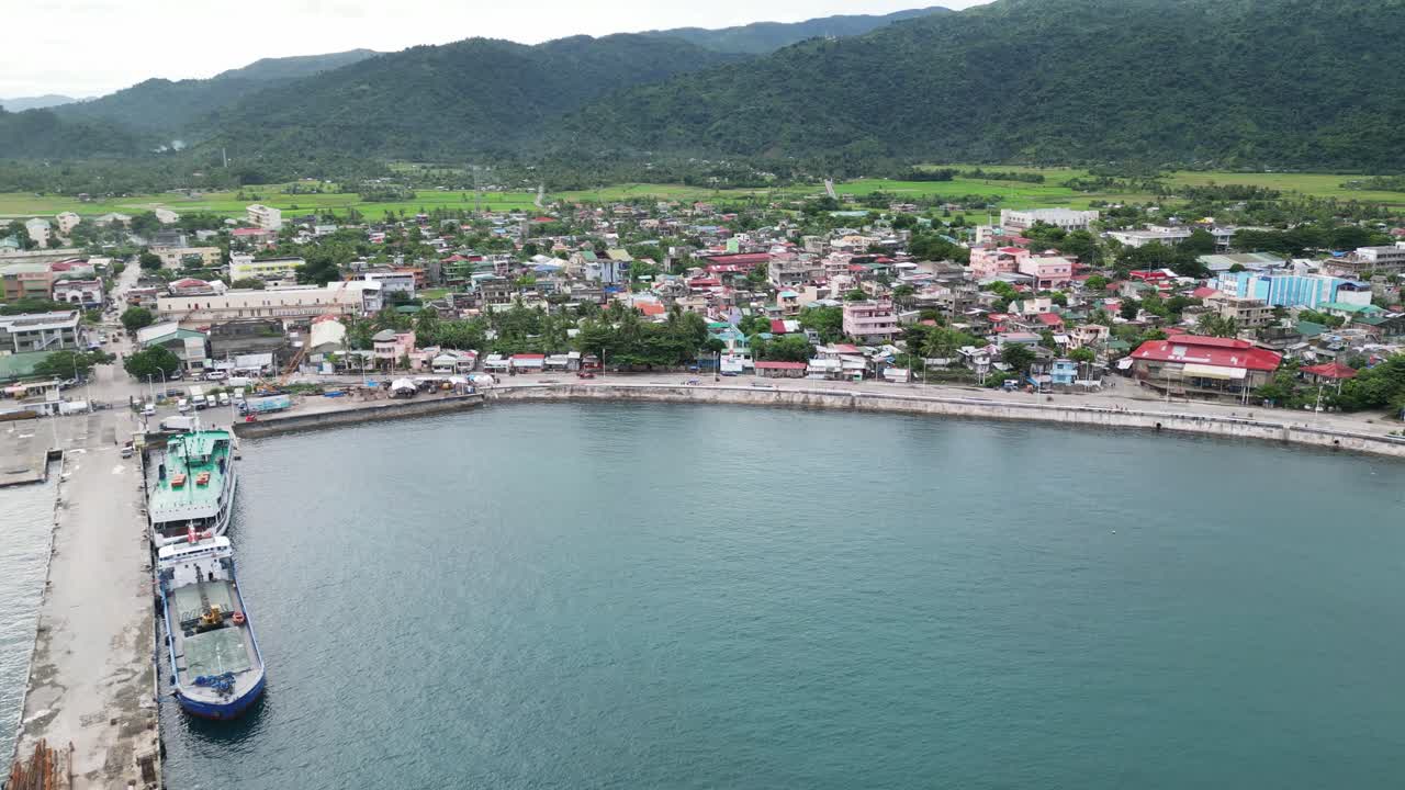 idílico disparo de drones aéreos de la ciudad isleña frente al mar con aguas turquesas de la bahía, puerto ocupado y exuberantes colinas cubiertas de jungla
