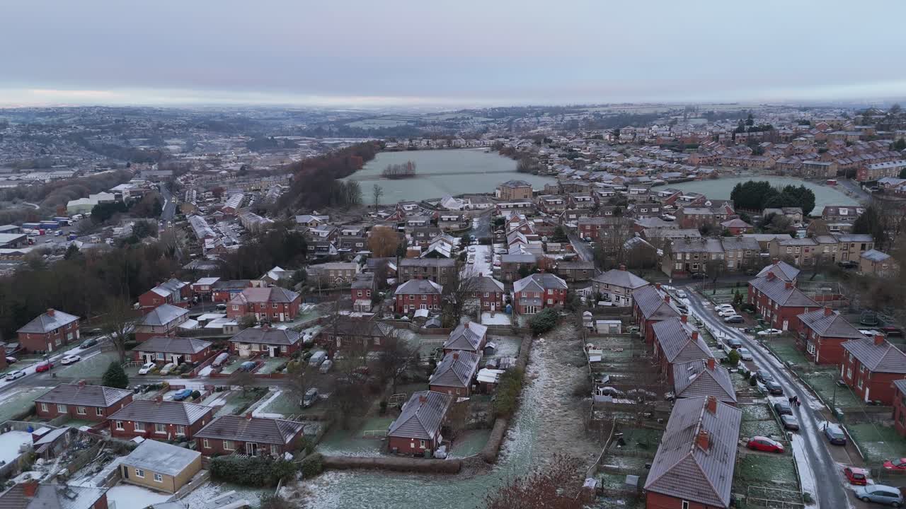 Vista invernale dal drone che riprende un tipico complesso residenziale urbano di proprietà comunale del Regno Unito, il Dewsbury Moore Council estate, con case a schiera in mattoni rossi e la zona industriale dello Yorkshire.