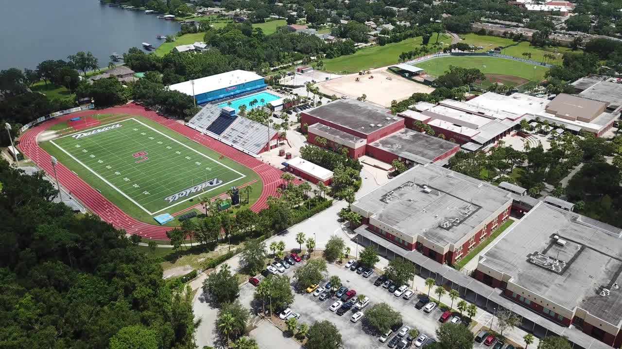 American High school with football field swimming pool and running track. Aerial
