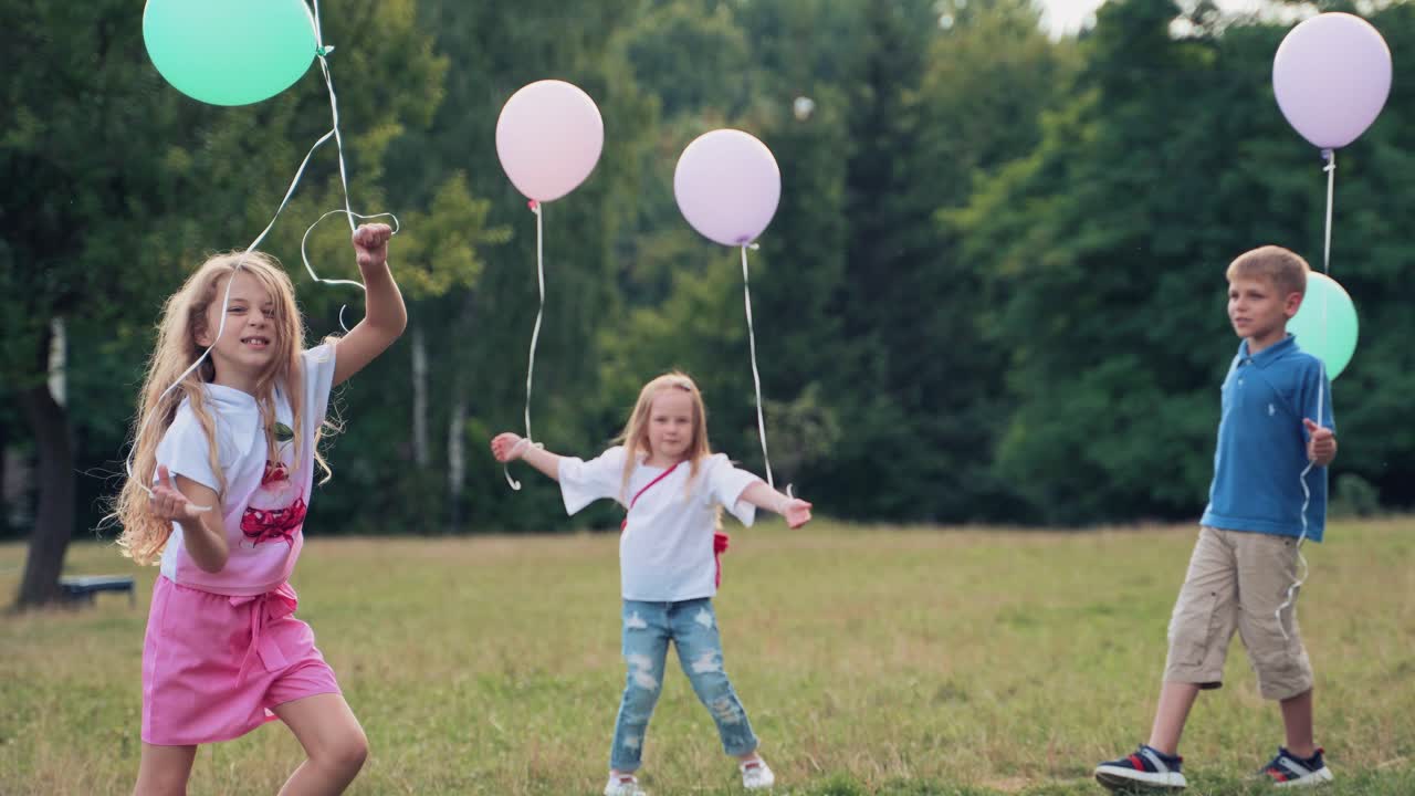 Happy cheerful children in the park on the lawn run, jump, play with colorful balloons. Children's holiday. boy playing with girls