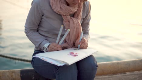 woman drawing flowers by the water