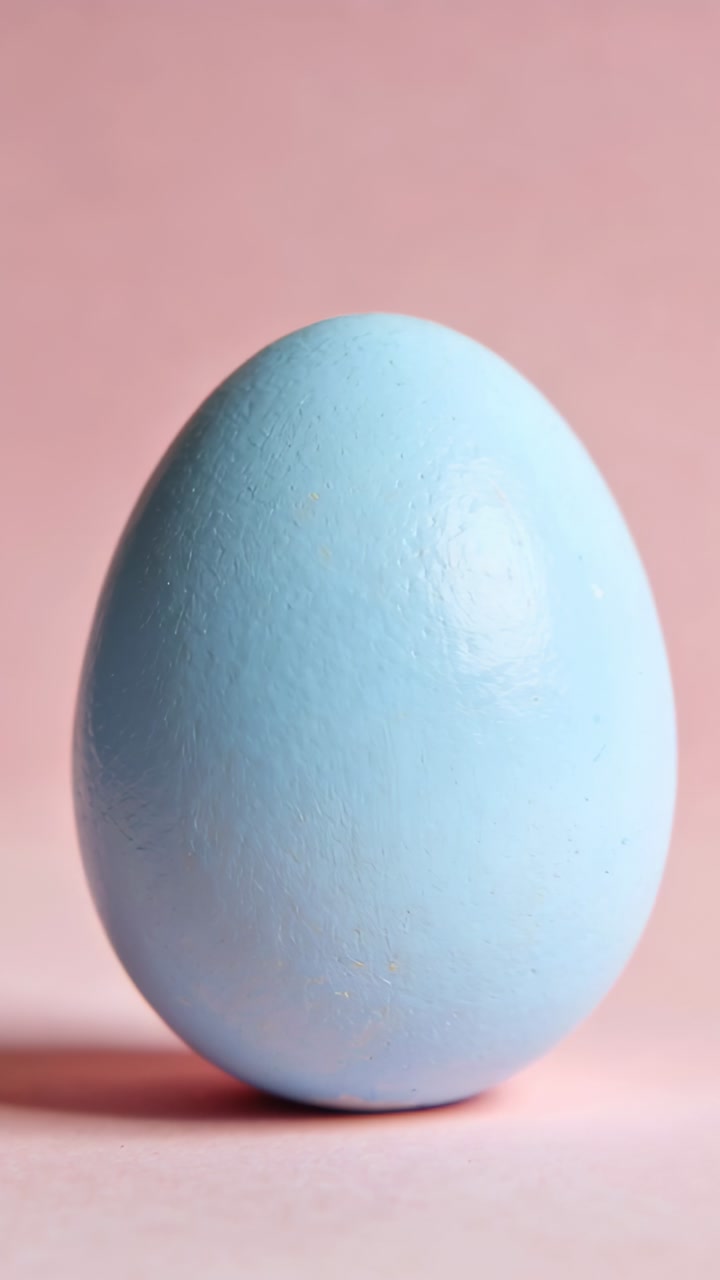 Vertical video: Shot pulling back pastel blue egg revealing shape, shadow and highlight for ads