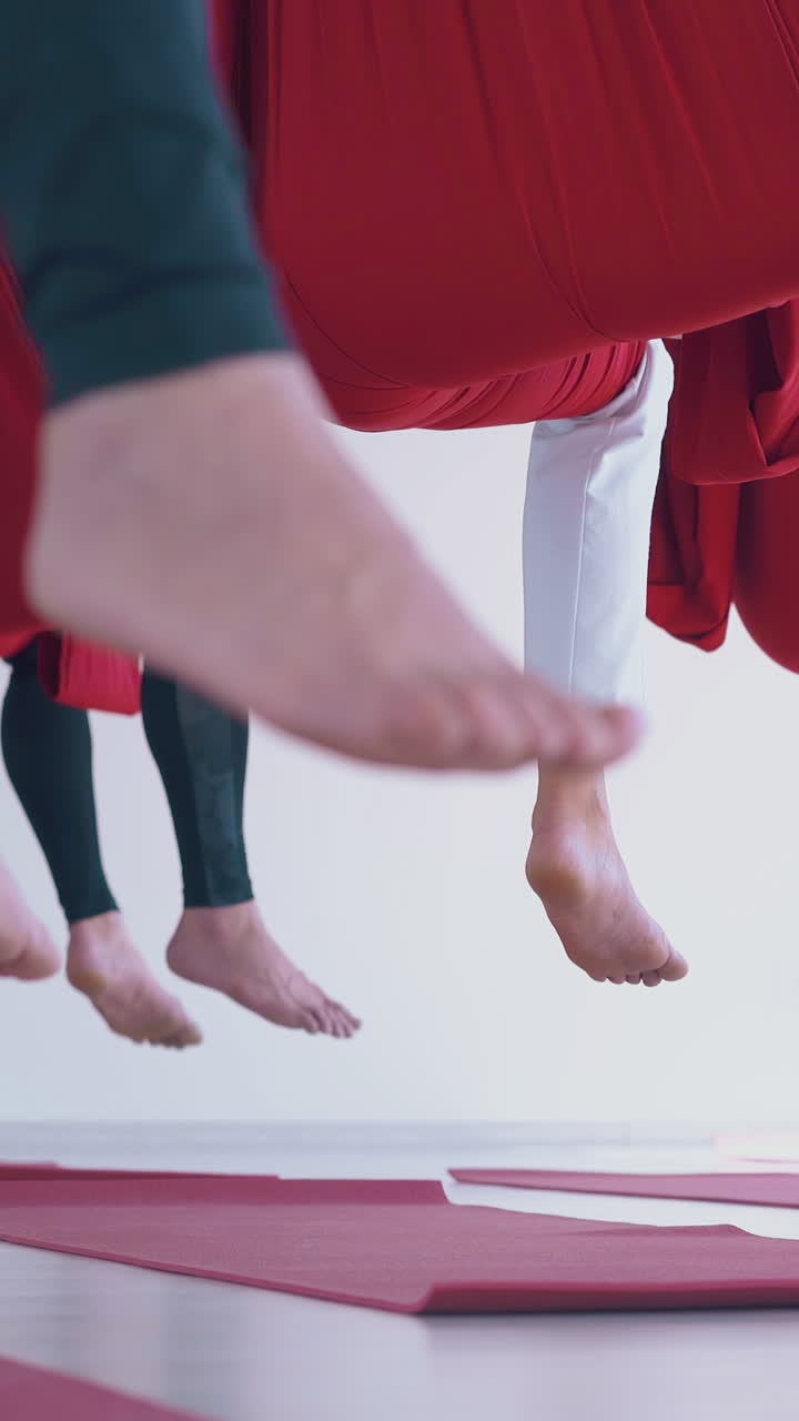 camera shows sportswomen bare feet sitting in special hammocks and meditating after hard fly yoga workout close view