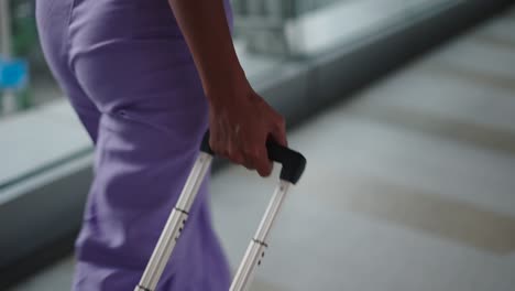 woman with purple pants and suitcase at airport