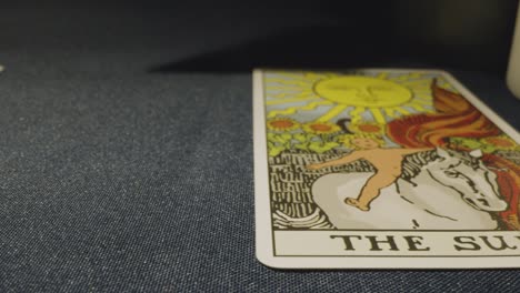 disparo de cerca de una persona que da lectura de cartas del tarot colocando cartas en la mesa con velas y cristales 1