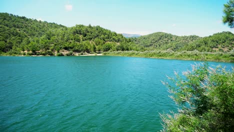 panning view of a natural lake in summer, with a wonderful blue sky and reflection in the water.