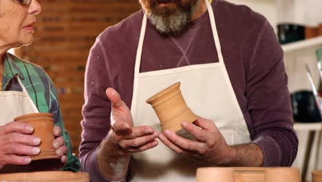 male and female potter interacting while examining a pot