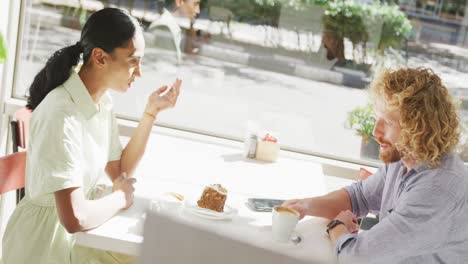 happy diverse couple drinking coffee and talking at a table in cafe