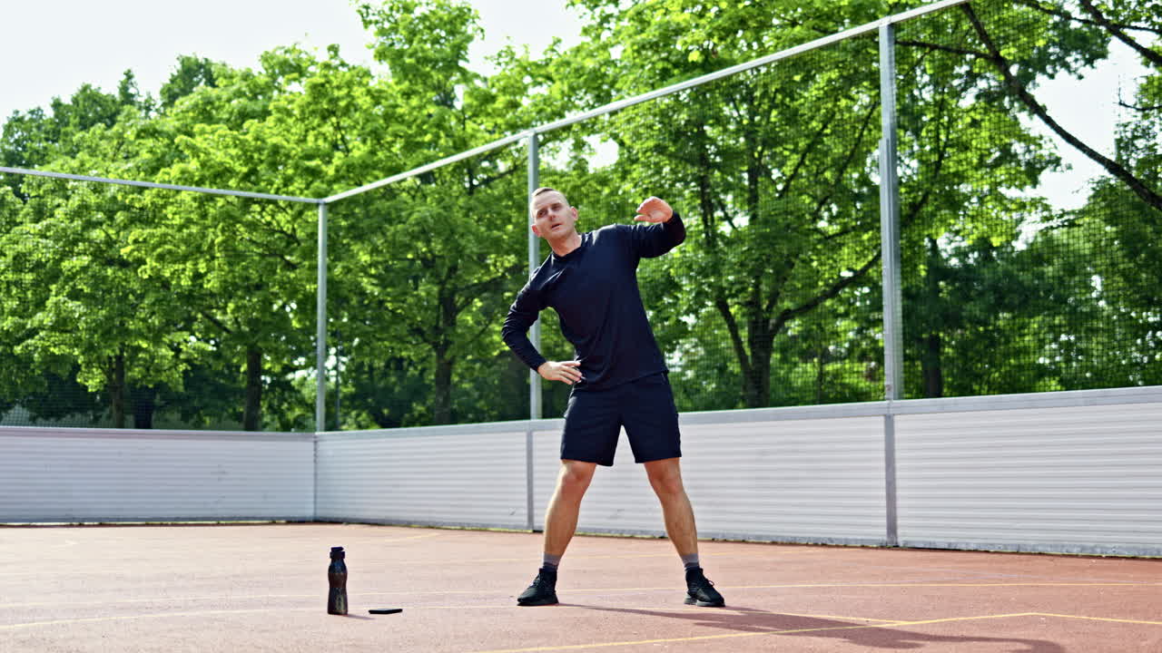 Giovane uomo attraente in pantaloncini neri che si allena sul campo sportivo. L'uomo fa sport all'aperto nel parco cittadino. Stile di vita sano.
