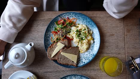 Alejar-El-Plato-De-Huevos-Revueltos,-Ensalada-Y-Pan-Del-Restaurante-Vegetariano-En-La-Mesa