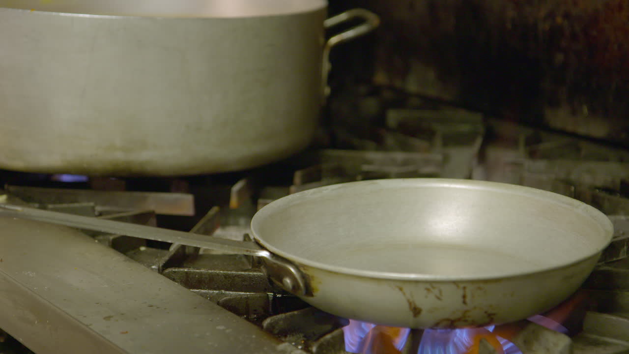 Chef loading pan with oil and vegetables and making big flame over gas