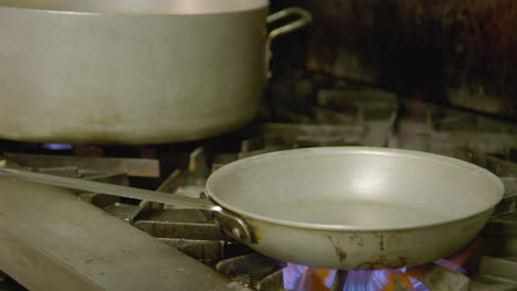 chef loading pan with oil and vegetables and making big flame over gas