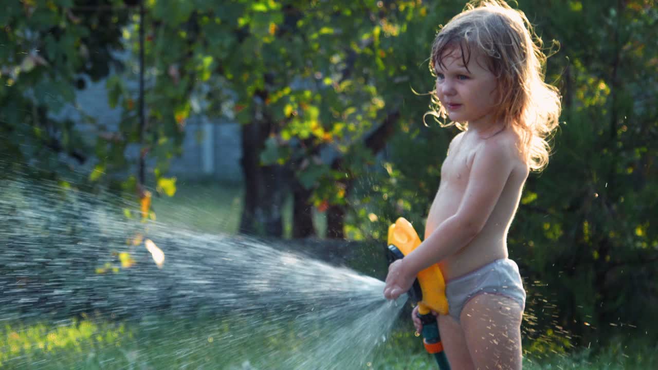 Child playing with water hose in garden