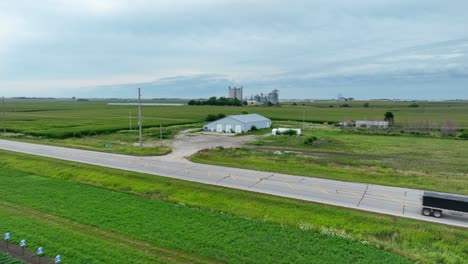 Semi-truck-with-trailer-full-of-corn,-grains,-and-animal-feed-driving-on-country-roads-in-midwest-USA-in-summer