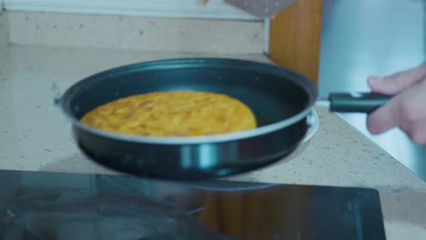 apagando la placa de cerámica y quitando la tortilla española de la sartén para colocarla en un plato