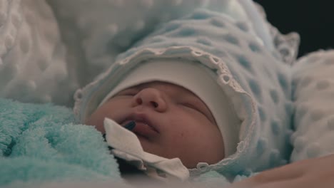 baby in blue clothes sleeps on soft blanket at home closeup