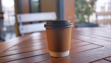 Blank-take-away-kraft-coffee-cup-on-table