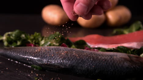 Fresh-whole-trout-on-a-bed-of-leaves-being-seasoned