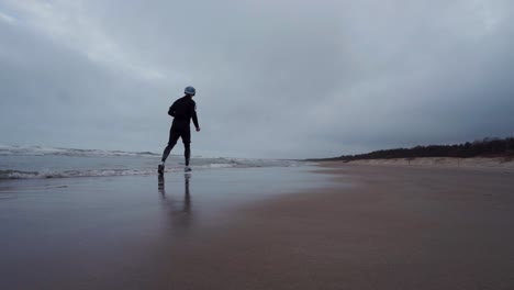 young man is running in the beach and he steps in the water