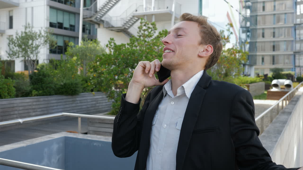 젊은 백인 남자가 밖에서 전화로 이야기하고, 흥분해 보입니다.