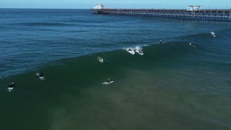 male surfer drops in on wave at oceanside pier