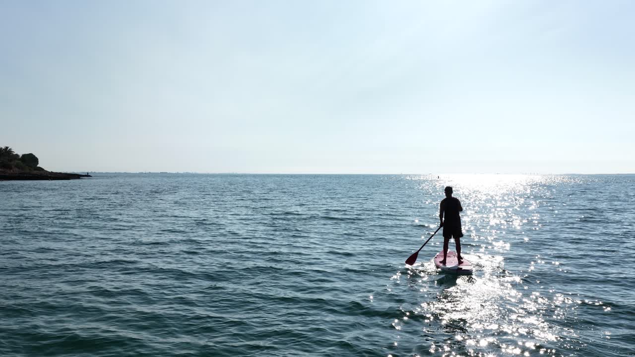 Sportsman paddle boarding on calm ocean during sunny day