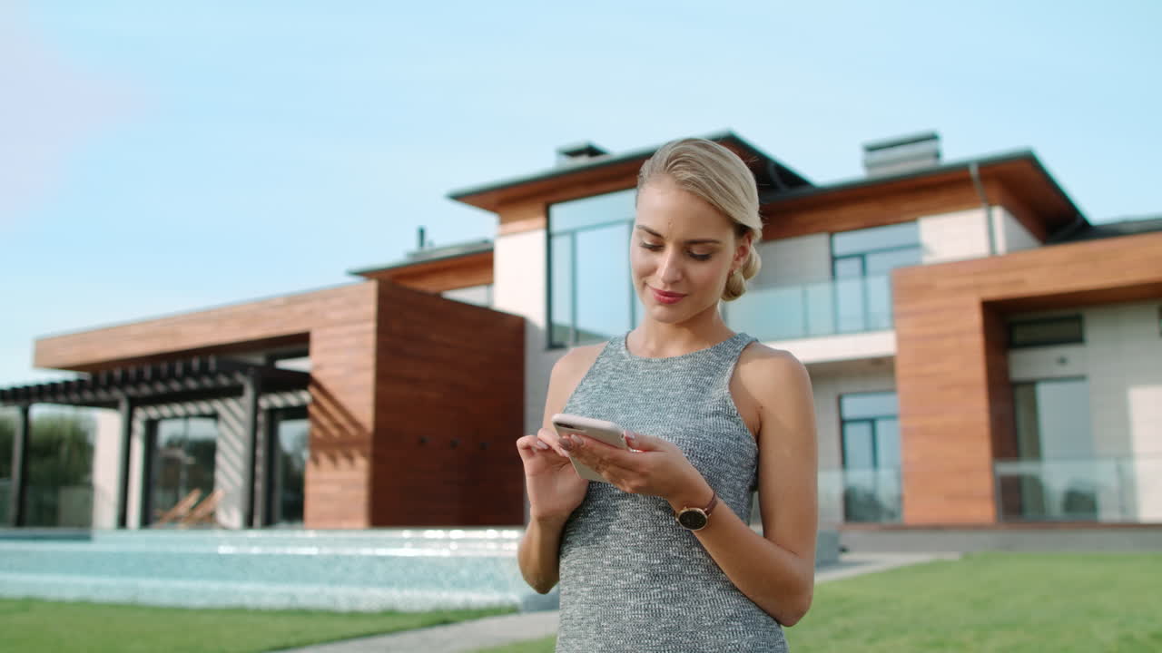 Cheerful woman using mobile phone at luxury apartment.
