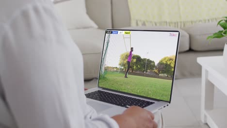 video de un hombre caucásico sentado en el sofá y viendo fútbol en la computadora portátil en casa
