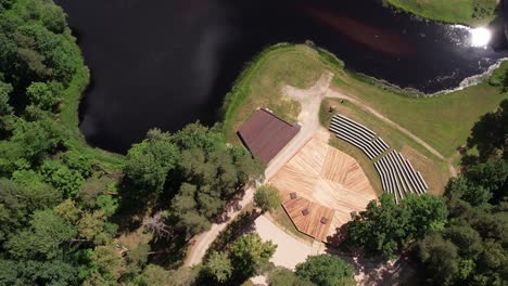 Aerial-view-of-Diklu-Stage-in-Dikli-village,-showcasing-the-open-air-performance-venue-surrounded-by-lush-greenery-and-nearby-buildings