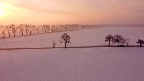 Tráfico-Ligero-Por-La-Mañana-En-Una-Carretera-Local-A-Través-De-Campos-Cubiertos-De-Nieve-Al-Amanecer