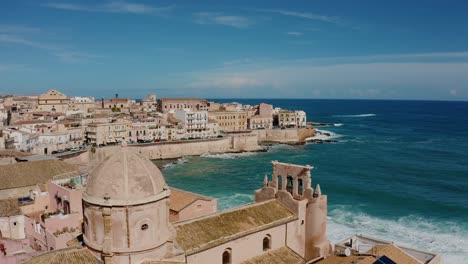 flying around cathedral tower in ortigia island. chiesa dello spirito santo. aerial drone shot of historic old town by the mediterranean sea in syracuse. unesco world heritage site in sicily.