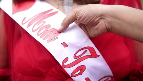 closeup view of husband showing "mom to be" sachet on his wife in a maternity photoshoot