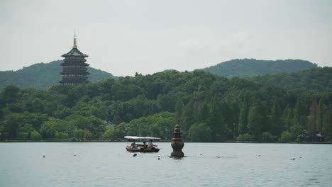 Leifeng-pagoda,-tourist-boat-and-one-of-the-Three-Stone-Pagodas-from-the-Three-Pools-Mirroring-the-Moon-West-Lake-Hangzhou-China