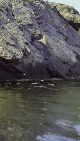 Calm water reflecting rugged rock formations at a tranquil shoreline