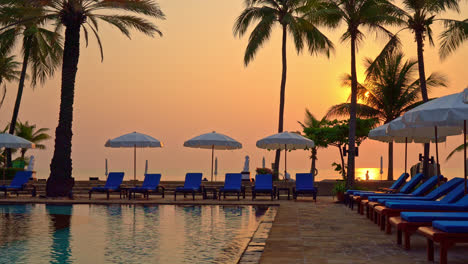 bed-pool-and-umbrella-around-swimming-pool-with-sunset-or-sunrise-sky