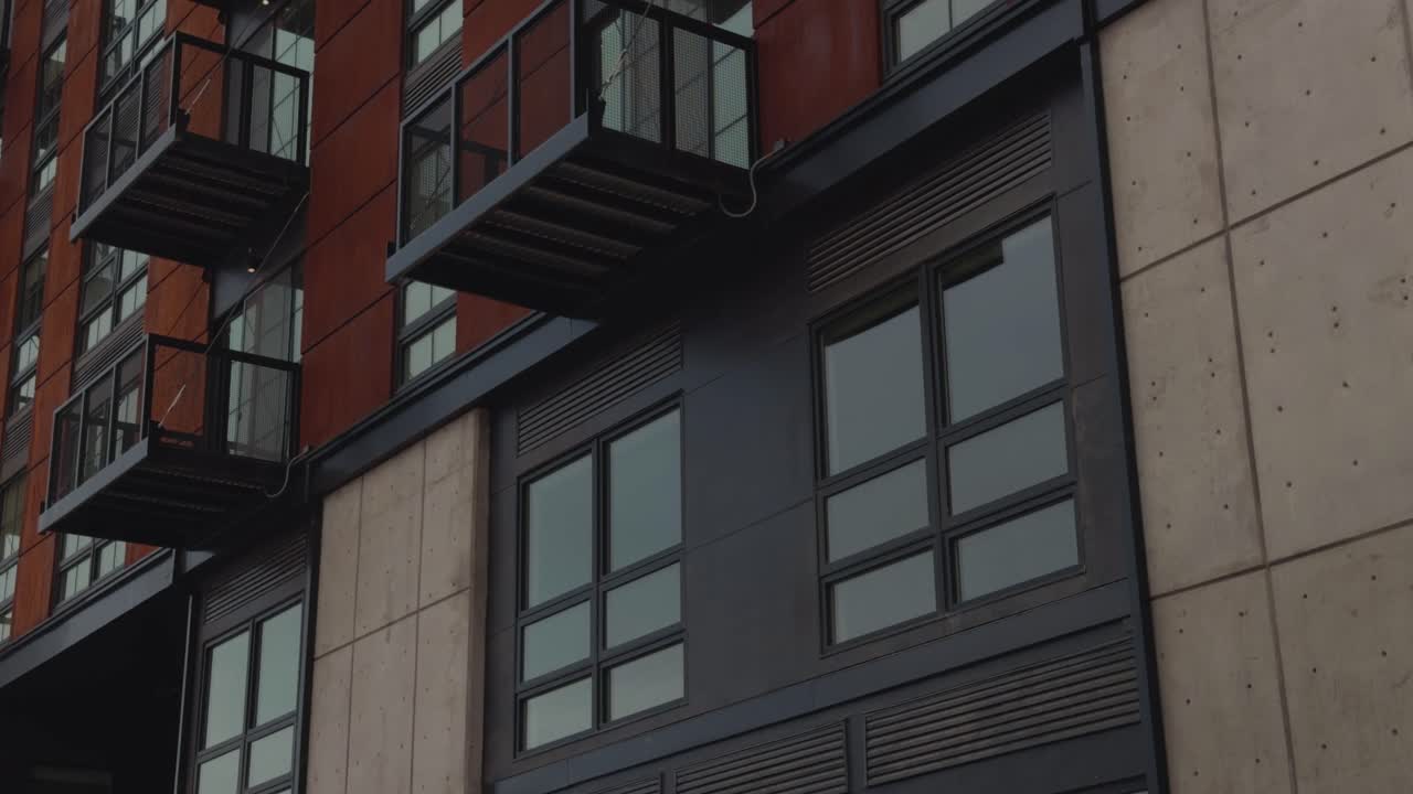 Panoramica lenta e costante verso l'alto che rivela balconi sovrapposti su un moderno edificio di appartamenti urbano