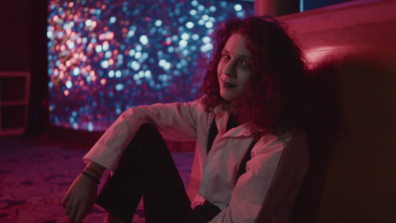 un joven sentado en el suelo mirando a la cámara.